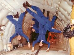 three men in blue jumpsuits are jumping into the air