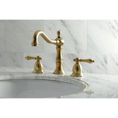 a bathroom sink with two faucets and marble counter top