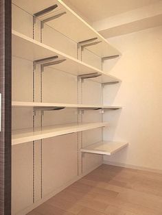 an empty room with white shelving and wood flooring