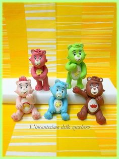 five small teddy bears sitting on top of a white board with yellow and green stripes