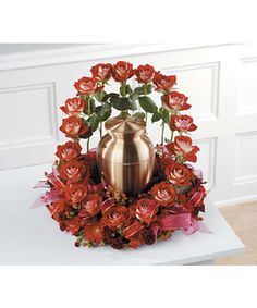 a gold vase filled with red flowers on top of a white table