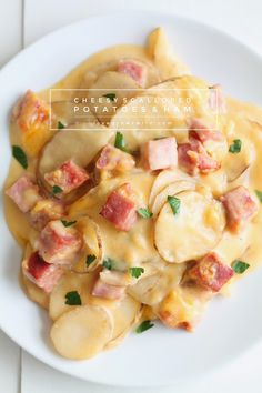 a white plate topped with potatoes and ham covered in cheese sauce, garnished with parsley