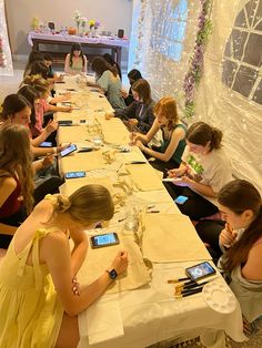 a group of people sitting at a long table with cell phones in their hands and writing on paper