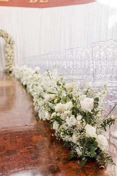 white flowers are lined up along the edge of an aisle