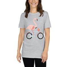 a women's t - shirt with a pink flamingo riding a bike on it