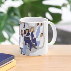 a coffee mug with an image of people on it sitting on a table next to some books