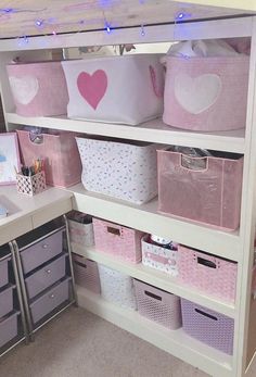 a white shelf filled with lots of pink bins and baskets on top of it