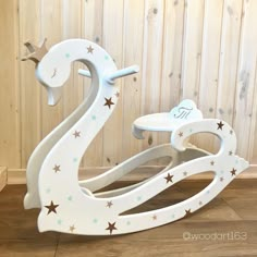 a white rocking horse with stars on the sides and a wooden wall in the background