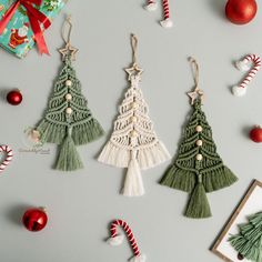 three christmas tree ornaments hanging from strings next to candy canes