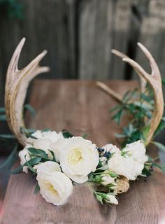 an antler headpiece with white flowers and greenery is featured in this postcard