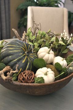 a bowl filled with white and green pumpkins on top of a dining room table