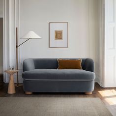 a living room with a blue couch and lamp on the side table in front of it