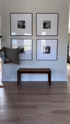 a woman holding a pillow in front of three pictures on the wall above a bench