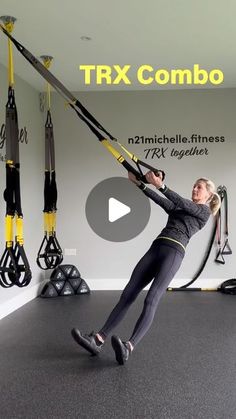 a woman is hanging on a rope in a room with other gym equipment and exercise mats