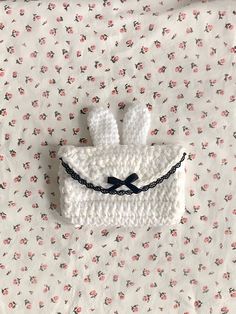 a white crocheted purse with two bunny ears on it sitting on a bed