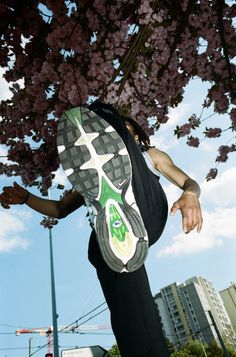 a person jumping in the air with their foot on a skateboard under a tree