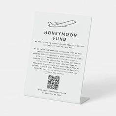 a white business card with the words honeymoon fund printed on it and an airplane in the background