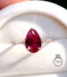 a close up of a ring with a red stone in the middle and diamonds around it