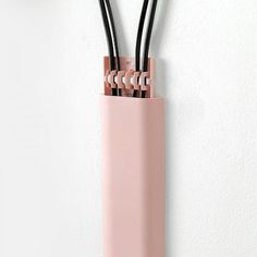 a pink vase with three black sticks sticking out of it's sides on a white wall