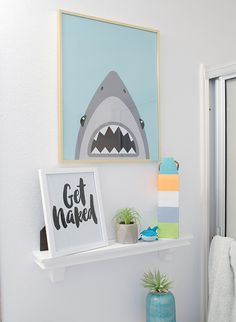 a bathroom with a shark poster on the wall next to a potted pineapple