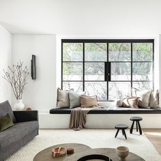 a living room filled with furniture and a large window in the wall next to it