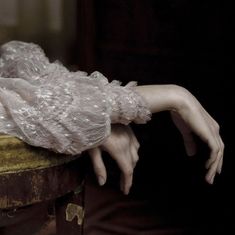 a woman's hand resting on top of an old suitcase with lace over it