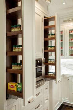 an open pantry door in a kitchen with white cabinets and wooden shelves filled with food