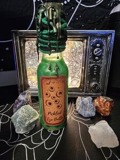 a green bottle with writing on it sitting next to some rocks and a small box