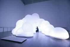 a person sitting on the floor in front of a large white cloud shaped structure with lights