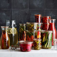 many jars filled with different types of vegetables and fruits next to each other on a counter