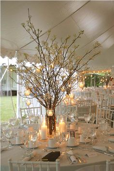 a table set up with candles and flowers in vases for an elegant wedding reception