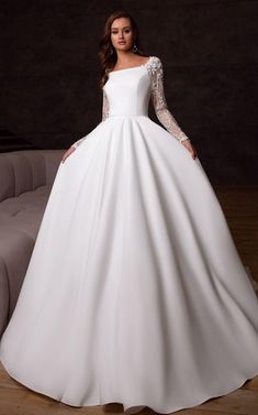 a woman in a white wedding dress standing on a couch with her hands on her hips