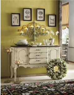 a white dresser sitting on top of a rug next to a wall with mirrors above it