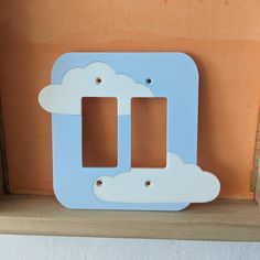 a blue and white double light switch plate with clouds on the front, and two holes in the middle