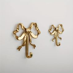 two gold colored metal items on a white surface, one has a bow and the other is a frog