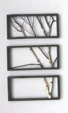 three metal frames with trees in them on a white surface and one is hanging from the wall