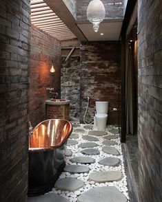 a bathroom with stone flooring and a copper bathtub in the middle of it