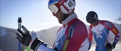 two skiers in red, white and blue uniforms with ski poles on their hands