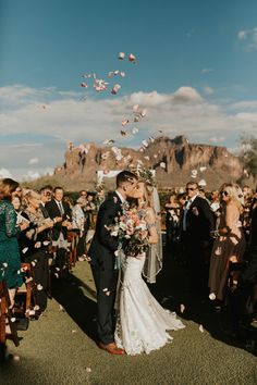 a bride and groom kissing under confetti thrown from the sky at their wedding