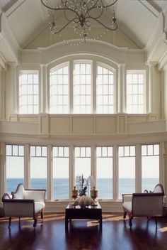 an image of a living room with large windows and chandelier hanging from the ceiling