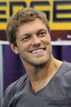 a man smiling for the camera in front of a sign