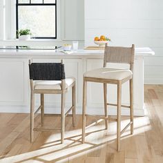 two chairs sitting on top of a hard wood floor next to a kitchen countertop