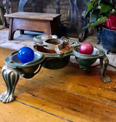 two metal bowls with apples on them sitting on a wooden floor