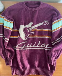 a purple sweater with an image of a guitar on it