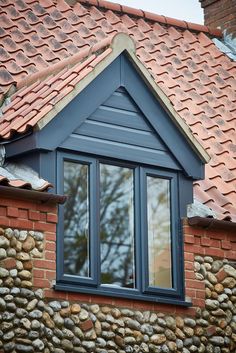 an image of a house that is made out of bricks and slates with a cat sitting on the window sill