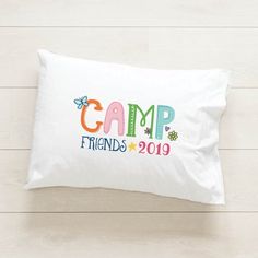 a pillow with the words camp friends on it sitting on a wooden floor next to a white wall