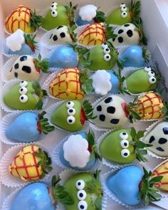 a box filled with lots of green and blue decorated chocolate covered strawberries on top of each other