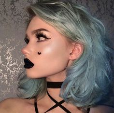 a woman with blue hair and black makeup is wearing a choker around her neck