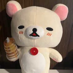 a white teddy bear holding an ice cream cone in it's right hand and wearing a red button on its left side