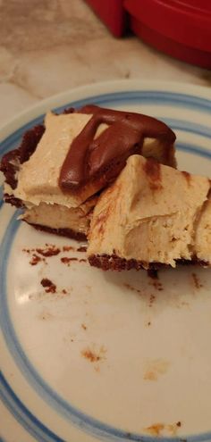 a piece of cake sitting on top of a white and blue plate with chocolate frosting